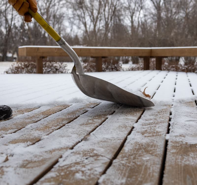 Man shovelling snow off timber decking